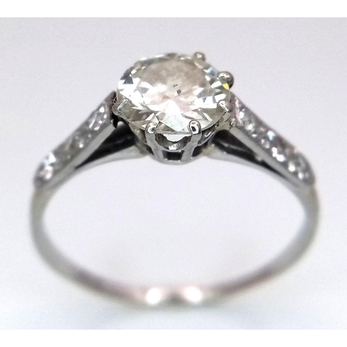 2083 - An 18K White Gold Diamond Ring. Central 1ct (approx) brilliant round cut tinted diamond with 0.15ct ... 