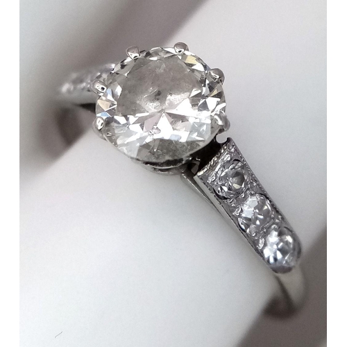 2083 - An 18K White Gold Diamond Ring. Central 1ct (approx) brilliant round cut tinted diamond with 0.15ct ... 