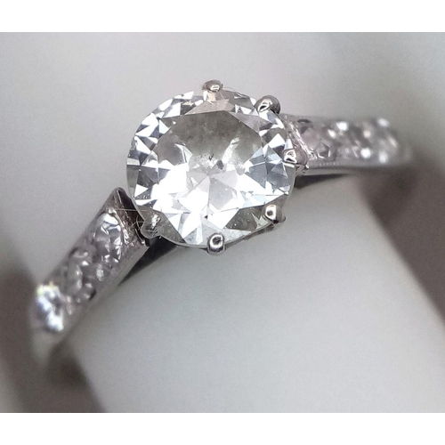 2083 - An 18K White Gold Diamond Ring. Central 1ct (approx) brilliant round cut tinted diamond with 0.15ct ... 