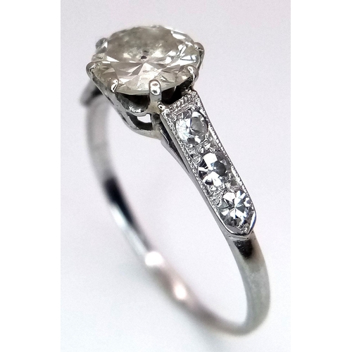 2083 - An 18K White Gold Diamond Ring. Central 1ct (approx) brilliant round cut tinted diamond with 0.15ct ... 