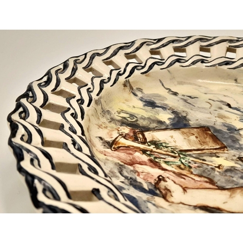 2104 - An Antique Ceramic Oval Dish with a Decorative Ribbon Style Surround. Hand-painted with a cherub 'at... 