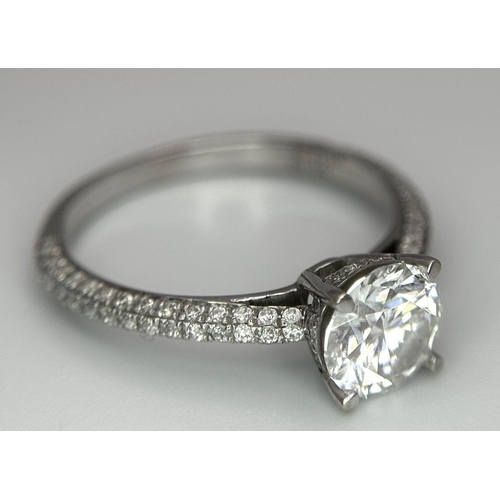 43 - An 18K White Gold Diamond Ring. Brilliant round cut 1ct diamond with a further 0.5ctw of diamonds on... 