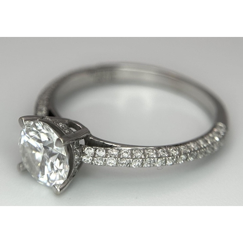 43 - An 18K White Gold Diamond Ring. Brilliant round cut 1ct diamond with a further 0.5ctw of diamonds on... 