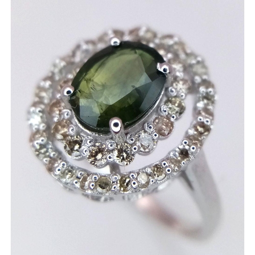 61 - A Green Peridot and Diamond Ring. Set in 925 Silver. Central oval peridot with two halos of diamonds... 