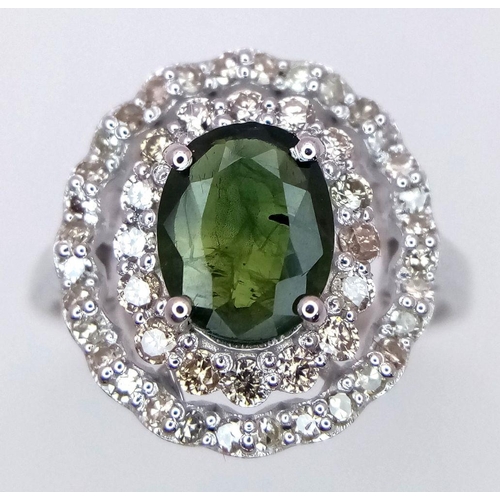 61 - A Green Peridot and Diamond Ring. Set in 925 Silver. Central oval peridot with two halos of diamonds... 