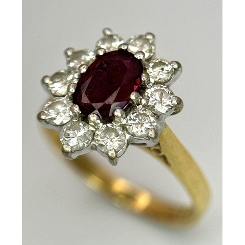 312 - An 18K Yellow Gold Diamond and Ruby Ring. Central ruby with a 10 stone diamond surround. Size I 1/2.... 