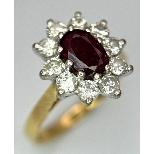 312 - An 18K Yellow Gold Diamond and Ruby Ring. Central ruby with a 10 stone diamond surround. Size I 1/2.... 