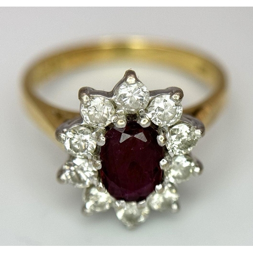 312 - An 18K Yellow Gold Diamond and Ruby Ring. Central ruby with a 10 stone diamond surround. Size I 1/2.... 