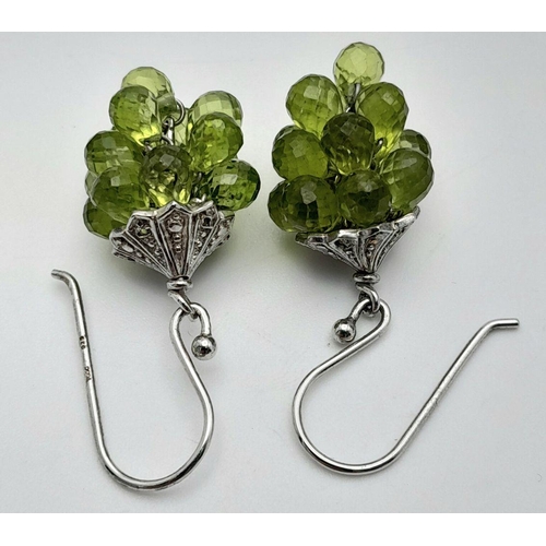 908 - A Unique Pair of Sterling Silver Peridot Set ‘Bacchus’ Design Earrings. 3.5cm Drop. 1.5cm Width.