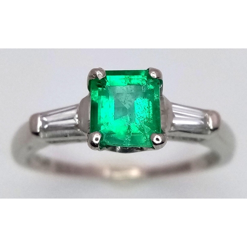 64 - A Platinum Emerald Ring. A 0.75ct Emerald Cut centre stone with tapered baguette diamond shoulders. ... 