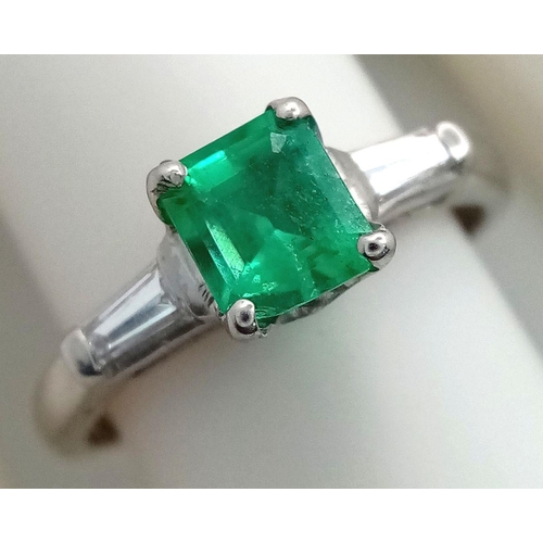 64 - A Platinum Emerald Ring. A 0.75ct Emerald Cut centre stone with tapered baguette diamond shoulders. ... 