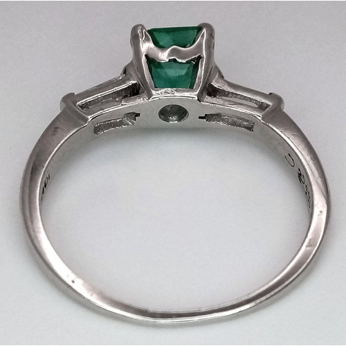 64 - A Platinum Emerald Ring. A 0.75ct Emerald Cut centre stone with tapered baguette diamond shoulders. ... 