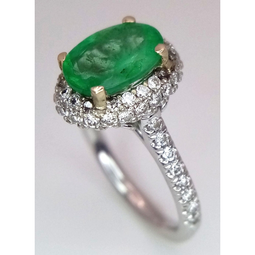 694 - A 14K White Gold, Emerald and Diamond Ring. A 1.3ct oval cut emerald with diamond surround and shoul... 