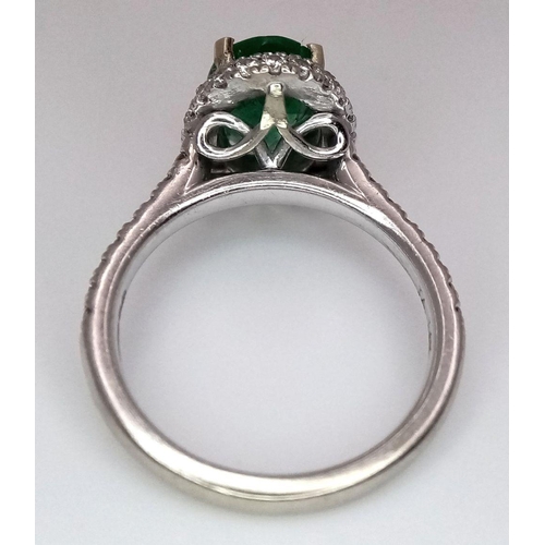 694 - A 14K White Gold, Emerald and Diamond Ring. A 1.3ct oval cut emerald with diamond surround and shoul... 