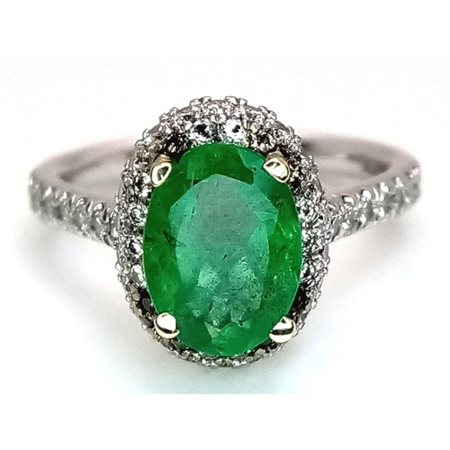 694 - A 14K White Gold, Emerald and Diamond Ring. A 1.3ct oval cut emerald with diamond surround and shoul... 