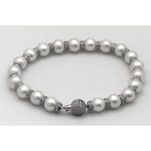 715 - An 18K White Gold, South Sea Pearl Bracelet with Diamond Cluster Spacers. 19.5g total weight.