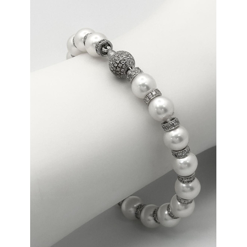 715 - An 18K White Gold, South Sea Pearl Bracelet with Diamond Cluster Spacers. 19.5g total weight.