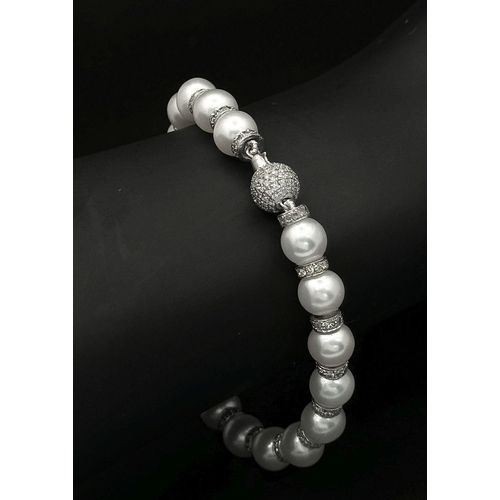 715 - An 18K White Gold, South Sea Pearl Bracelet with Diamond Cluster Spacers. 19.5g total weight.