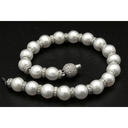 715 - An 18K White Gold, South Sea Pearl Bracelet with Diamond Cluster Spacers. 19.5g total weight.