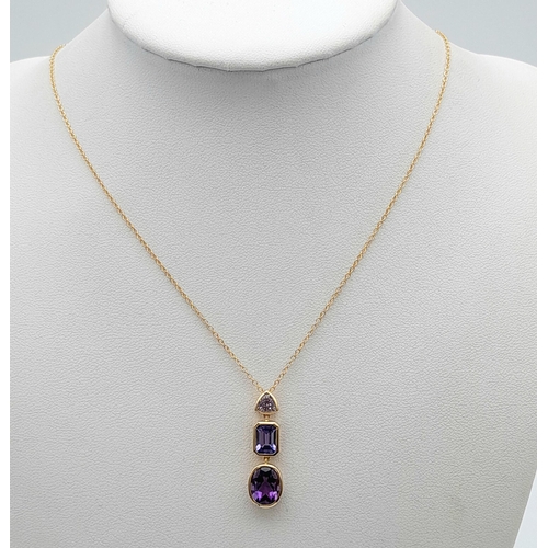 100 - AN 18K YELLOW GOLD TANZANITE & AMETHYST DROP PENDANT. 4.8G IN WEIGHT. APPROX. 45CM IN LENGTH. Ref: A... 