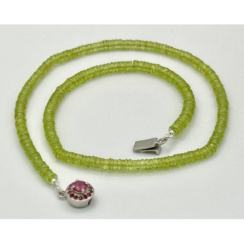 207 - A 90ct AAA quality peridot gemstone necklace featuring faceted peridot beads and ruby-accented clasp... 