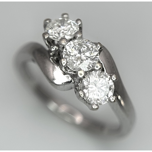 23 - AN 18K WHITE GOLD DIAMOND CROSSOVER TRILOGY RING. 1.20CT. 5G TOTAL WEIGHT. SIZE M. Ref: A/S 1195