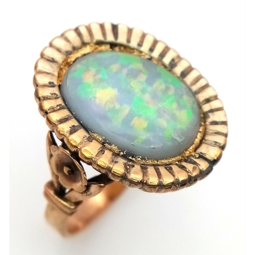 251 - A vintage or possibly older 9 K yellow gold ring, with a large (16x 12 mm) oval opal cabochon with w... 