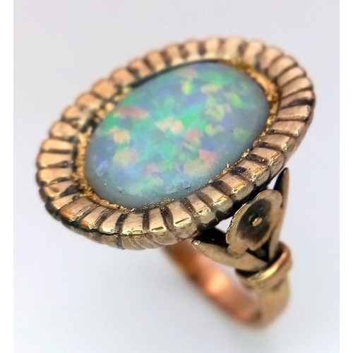 251 - A vintage or possibly older 9 K yellow gold ring, with a large (16x 12 mm) oval opal cabochon with w... 