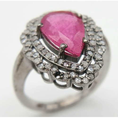 221 - A 925 silver ring featuring a 3.5ct pear-cut ruby, framed by two rows of intricate diamond accents. ... 