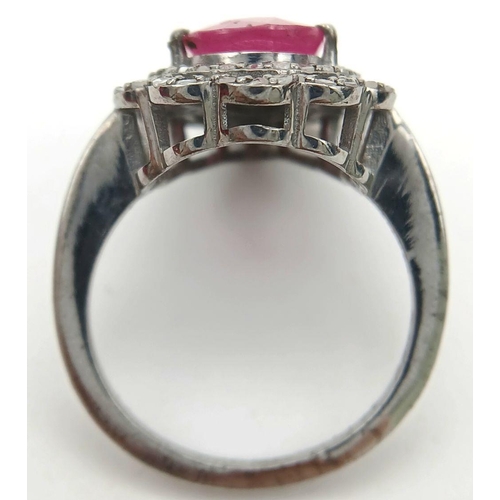 221 - A 925 silver ring featuring a 3.5ct pear-cut ruby, framed by two rows of intricate diamond accents. ... 