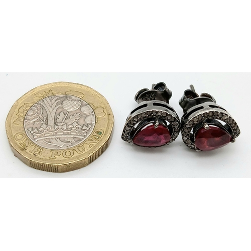 924 - A pair of 925 silver stud earrings featuring pear-cut ruby gemstones surrounded by a halo of sparkli... 