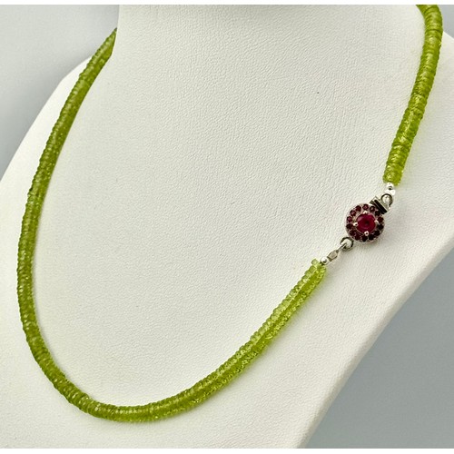 207 - A 90ct AAA quality peridot gemstone necklace featuring faceted peridot beads and ruby-accented clasp... 