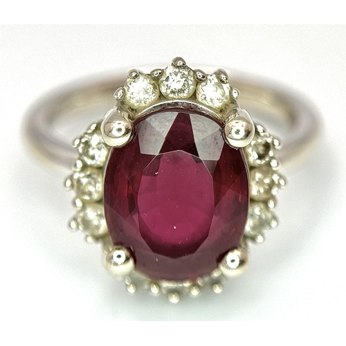 384 - A 14K White Gold, Garnet and Diamond Ring. Rich, oval cut central garnet with a twelve stone diamond... 