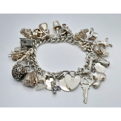 457 - A Sterling Silver Charm Bracelet with Heart Clasp. 25 charms, including: windmill, 21 key and cherub... 