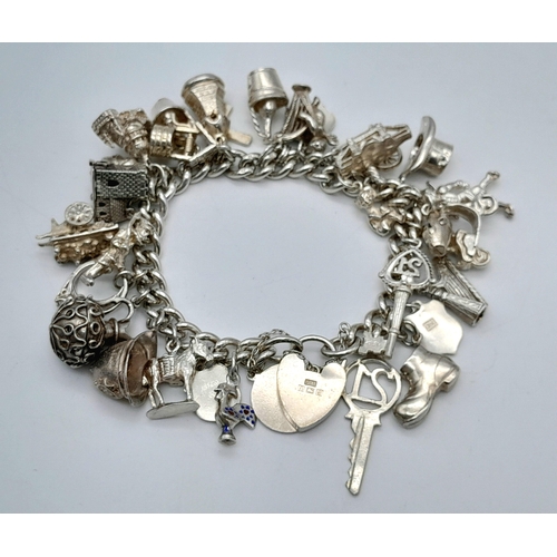 457 - A Sterling Silver Charm Bracelet with Heart Clasp. 25 charms, including: windmill, 21 key and cherub... 