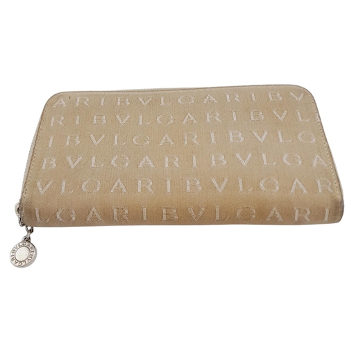 1043 - A Bvlgari Beige Mania Purse. Textile exterior with silver-toned hardware and zip top closure. Brown ... 