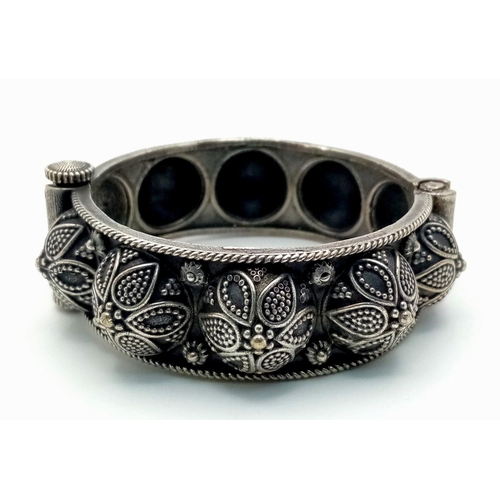 1556 - A white metal pull-out clasp bangle with intricate floral and leaf motifs. approx 6cm diameter.