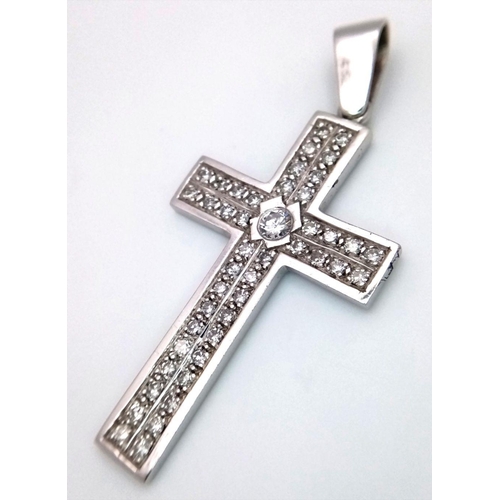 1312 - A 9K White Gold (tested) Diamond Cross Pendant. 0.5ct central brilliant round cut diamond with a fur... 