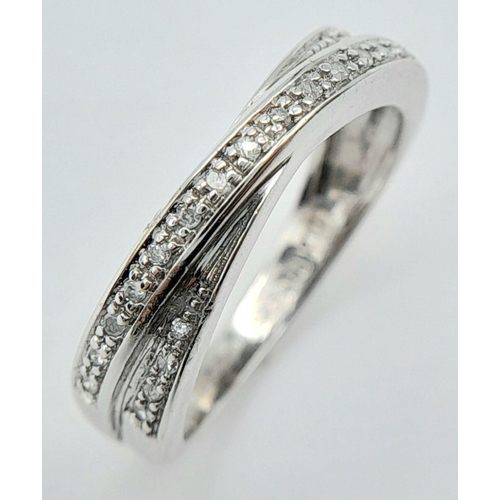 291 - A 9K WHITE GOLD DIAMOND SET CROSSOVER RING 2.7G TOTAL WEIGHT, SIZE M 1/2. Ref: SC 2014