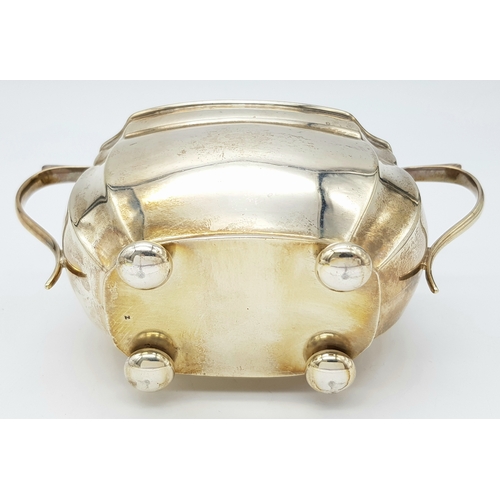 210 - A handsome Antique SOLID SILVER SUGAR BOWL. Standing on four Ball feet and having scroll trophy hand... 