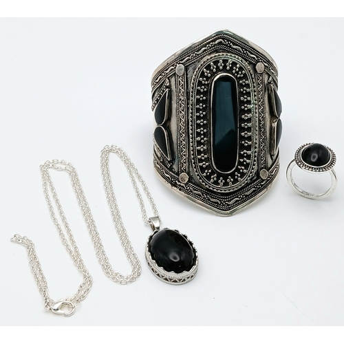 1663 - A Black Agate suite comprising a cuff, a pendant on chain, and a ring. Approx. measurements: ring si... 