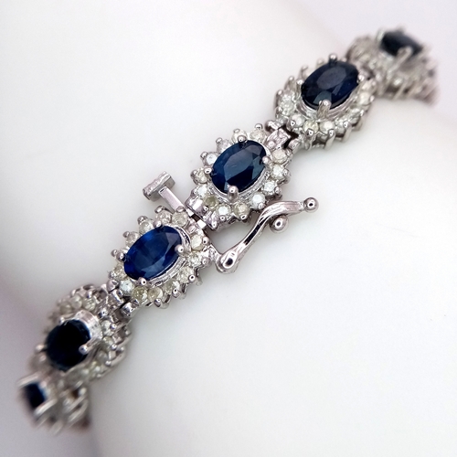 663 - A Beautiful 14K White Gold, Sapphire and Diamond Bracelet. Seventeen oval cut sapphires each with a ... 