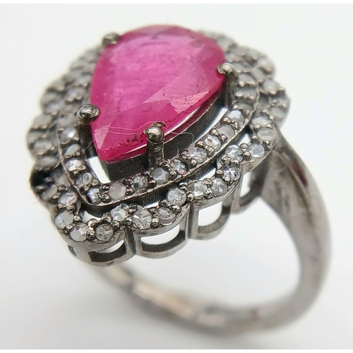 775 - A 925 silver ring featuring a 3.5ct pear-cut ruby, framed by two rows of intricate diamond accents. ... 