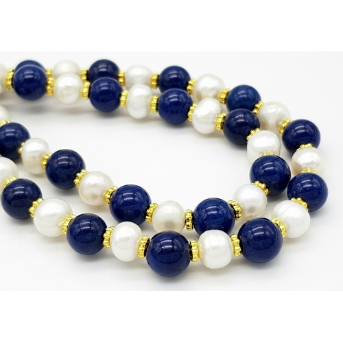 296 - A Lapis Lazuli and Cultured Pearl Matinee Length Necklace. 7/8mm pearls and lapis beads. Gilded spac... 