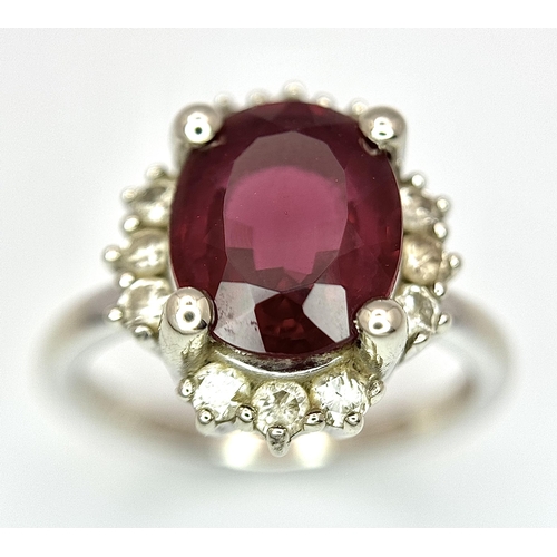 384 - A 14K White Gold, Garnet and Diamond Ring. Rich, oval cut central garnet with a twelve stone diamond... 