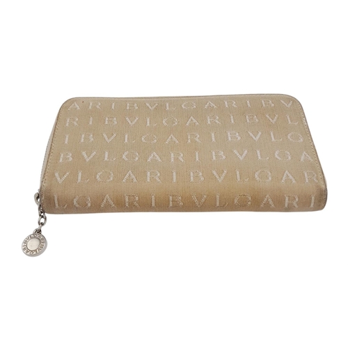 1043 - A Bvlgari Beige Mania Purse. Textile exterior with silver-toned hardware and zip top closure. Brown ... 