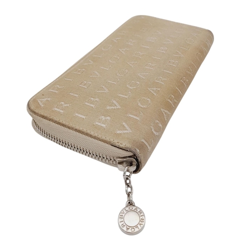 1043 - A Bvlgari Beige Mania Purse. Textile exterior with silver-toned hardware and zip top closure. Brown ... 