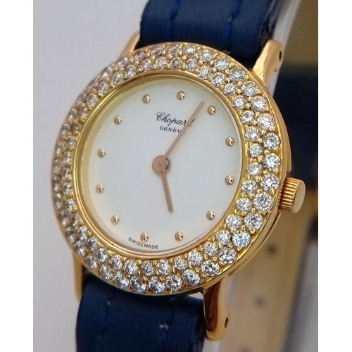 79 - An 18K Gold and Diamond Chopard Ladies Quartz Watch. Blue leather strap. 18k gold case with two halo... 