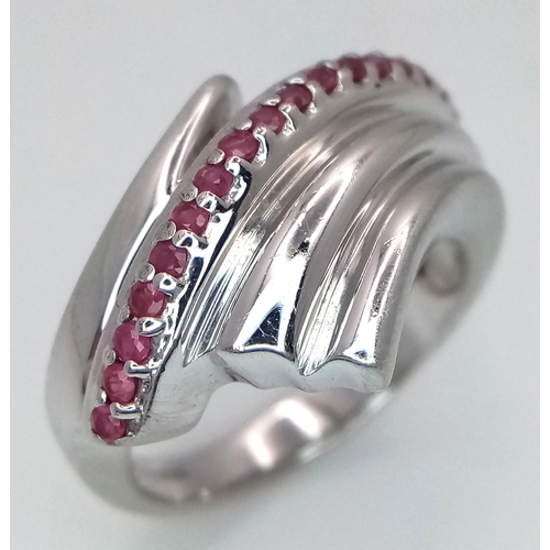 851 - A Hallmarked 2007 Sterling Silver and Ruby Set Wave Design Ring Size O. The Ring is set with 18 Roun... 