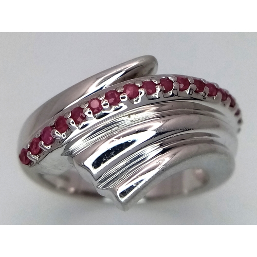 851 - A Hallmarked 2007 Sterling Silver and Ruby Set Wave Design Ring Size O. The Ring is set with 18 Roun... 